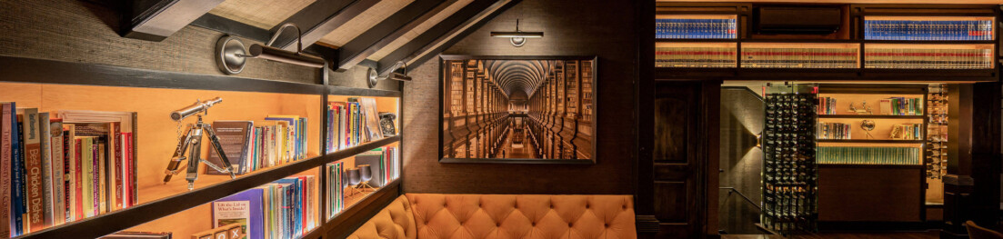 Illuminated bookshelves and a long dining table.