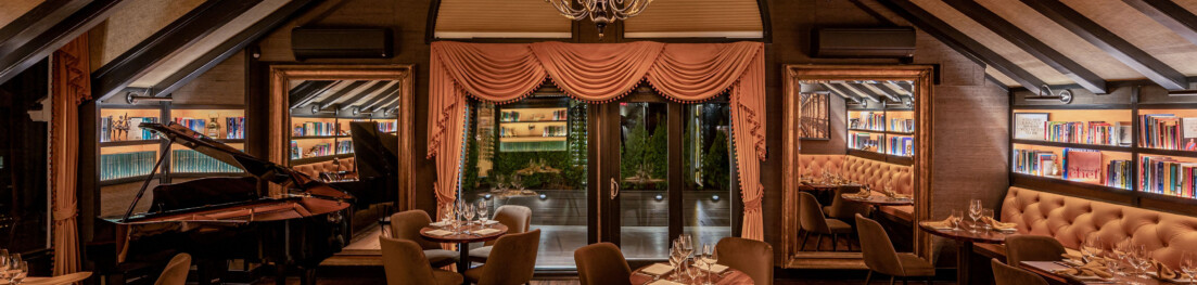 A dimly lit dining area with tables and a piano.