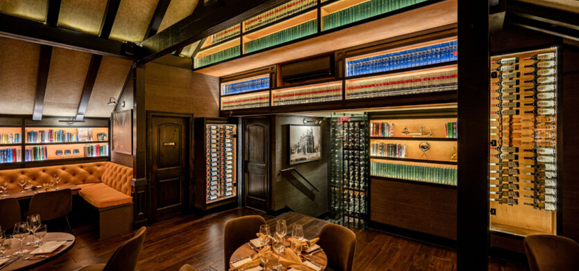 A bistro table overlooking a wine case and a selection of books.