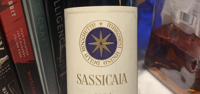A bottle of Sassicaia in front of books.