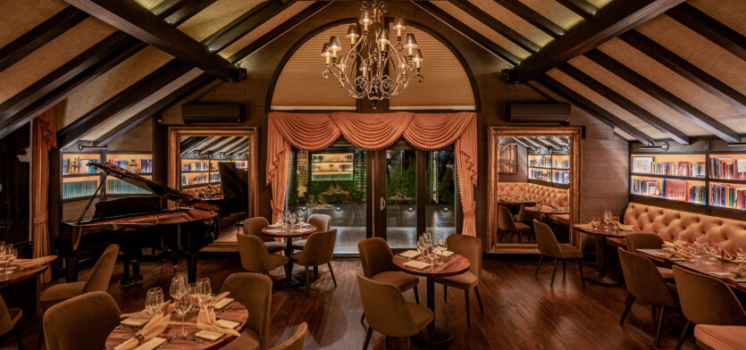 A dimly lit dining area with tables and a piano.